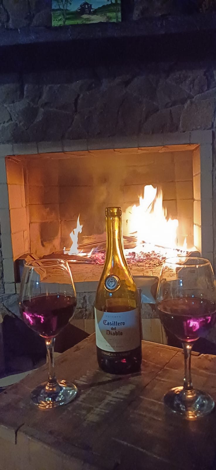 Vinho e taças em frente à lareira acesa no Celeiro